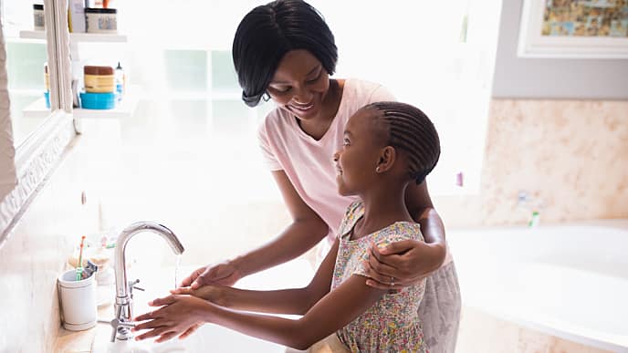 Woman and daughter washing their hands