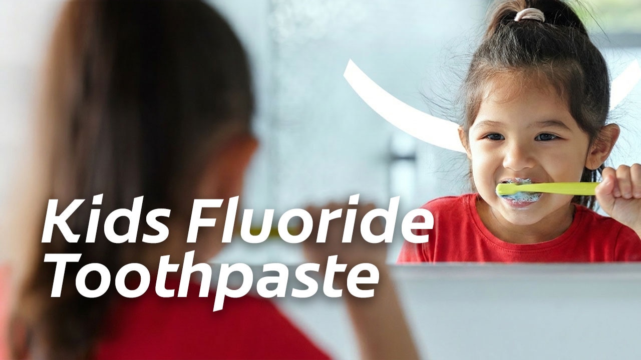 Young girl smiling while brushing her teeth in the mirror, with text reading "Kids Fluoride Toothpaste".