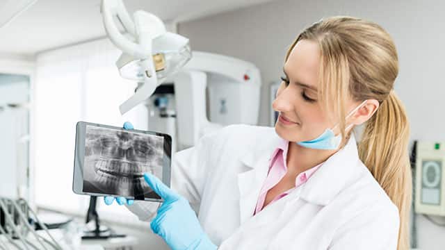 A female dentist showing an x-ray on tablet computer