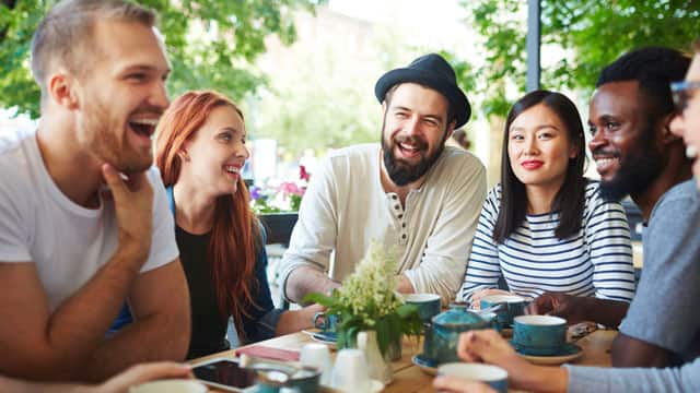 A group of friends smiling and talking at an outdoor table