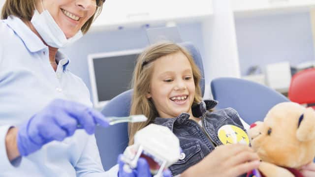 Dental professional showing dentures to a kid