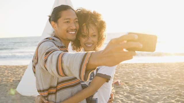 Joven pareja sacandose una selfie en la playa