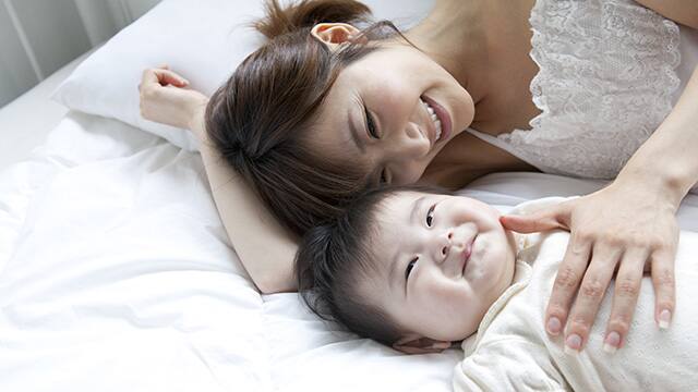 madre sonriendo acostada con su bebe 