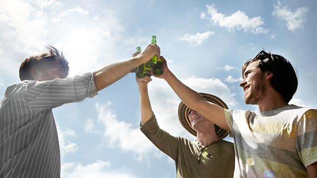 Three young men holding beers outdoors