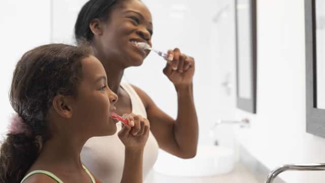 Madre enseñando a su hija a cepillarse los dientes