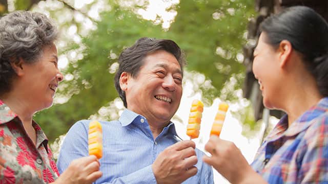 familia asiática de tres sonriendo y comiendo helado