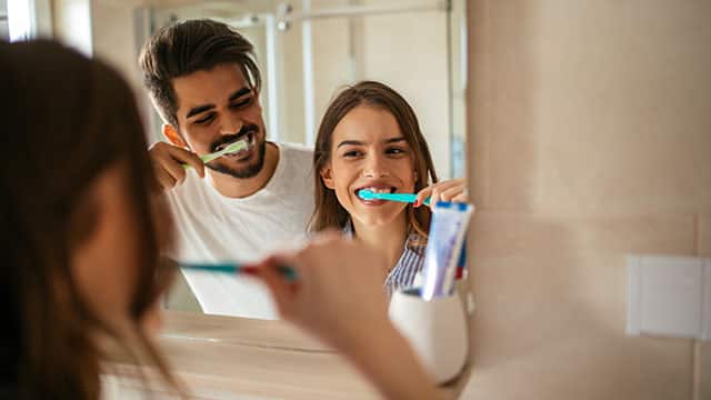 A young couple brushing teeth in the bathroom