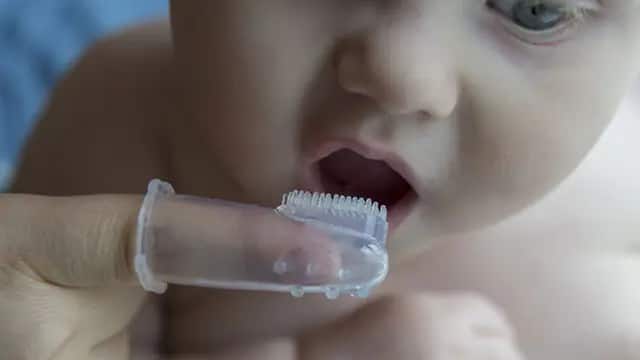 baby getting their teeth brushed