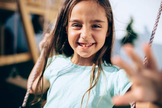 Happy girl swinging and showing a pain-free smile