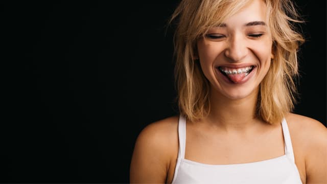 Young woman with braces sticking out her tongue