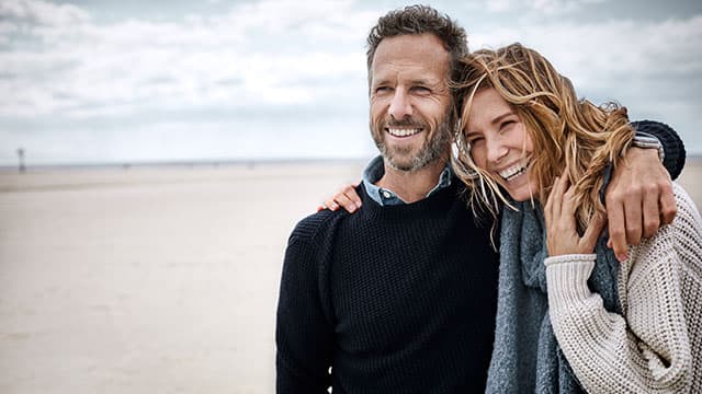 Adult couple smiling and embraced on the beach