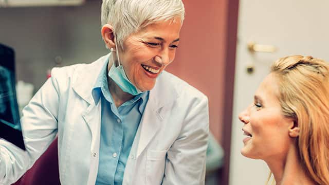 A female dentist is talking with female patient