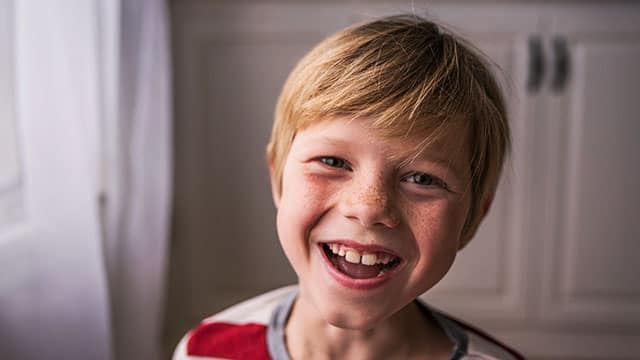 Young boy smiling and wearing a red and white striped shirt