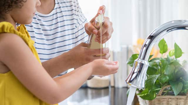 A mom helps daughter to wash her hands