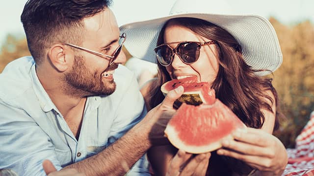 A couple eating a watermelon outdoors