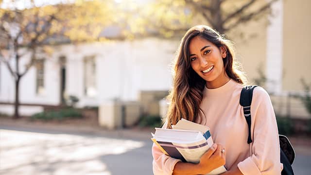 A student carrying lots of books on college campus