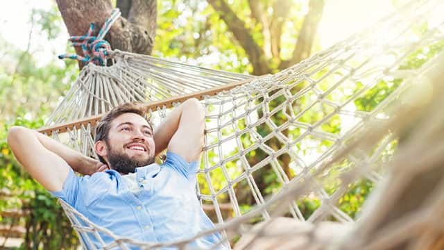 a man laying down on a hammock outdoor