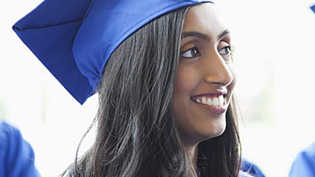 Group of graduates wearing blue cap and gowns smiling