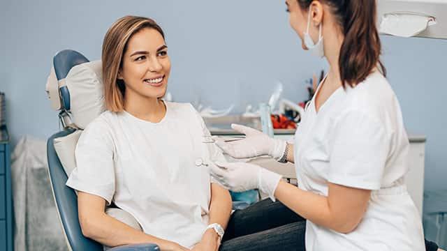 A dentist woman talking to female patient in dental office
