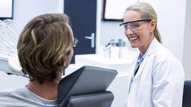 A female dentist interacting with a male patient in a dental office