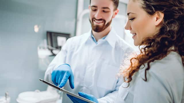 A dentist showing a tablet to a female patient at the dental clinic