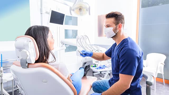 young Dentist treating a female patient in a dental chair