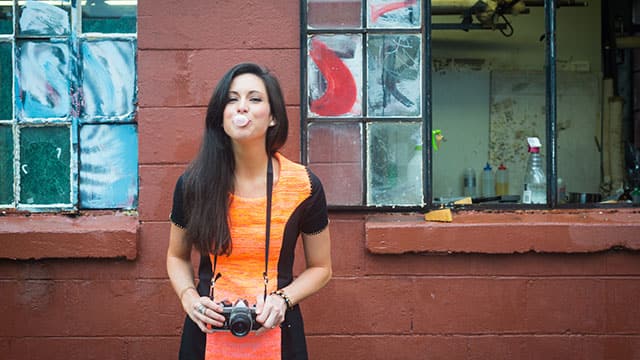 Happy woman chewing gum and holding a camera