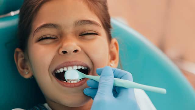 Young girl having her teeth examined by a pediatric dentist