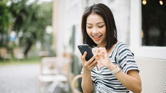 A young woman is using a phone outside