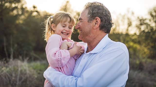 Grandpa holding a child in a field