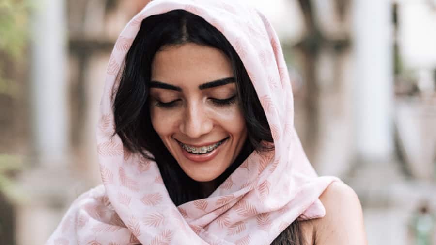Smiling teenage girl with braces enjoying a lollipop with her friend in the background