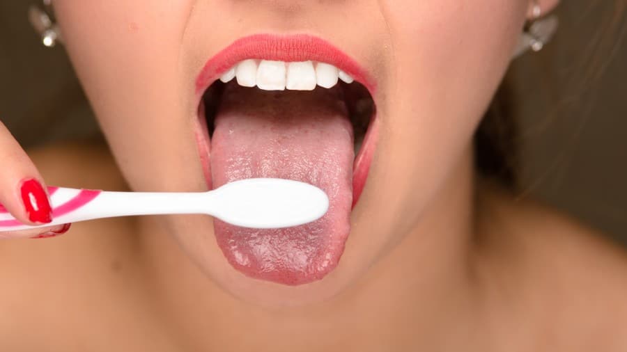 A lady using toothbrush for tongue cleaning