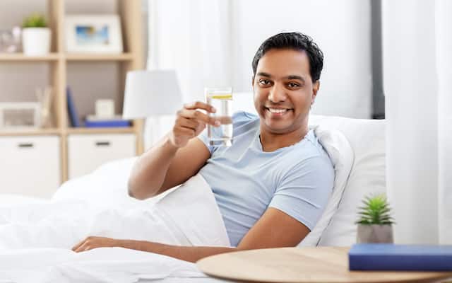 Man holding a glass of water, addressing dry mouth caused by dehydration