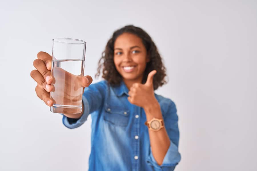 Jovem feliz com um grande sorriso, segurando copo de água