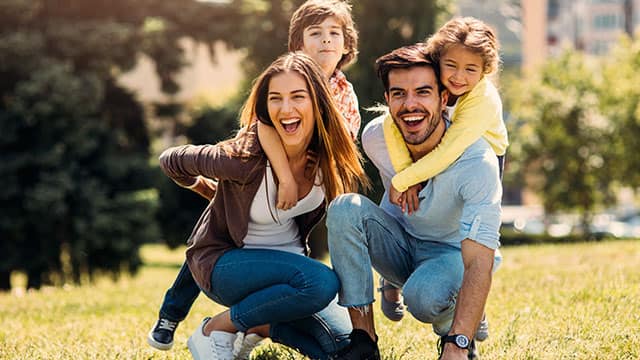Parents with two kids smiling outdoors