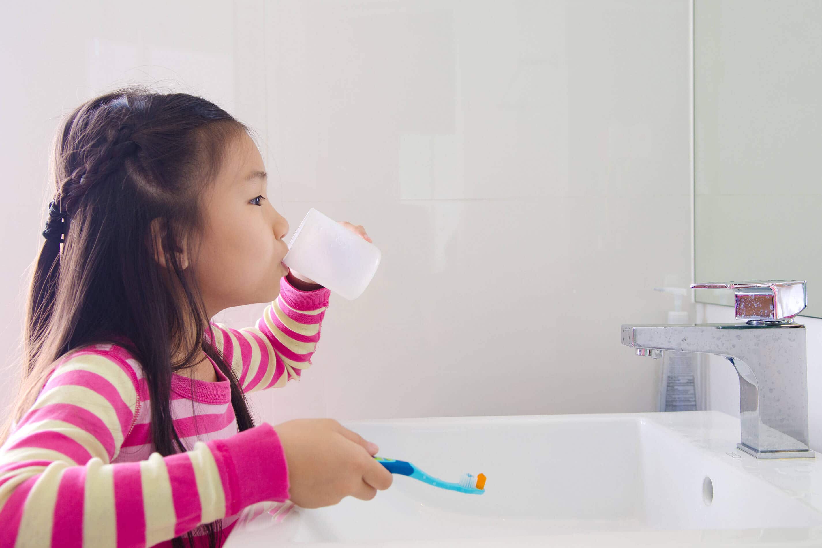 Little girl rinsing her mouth with warm salt water for oral hygiene and toothache relief
