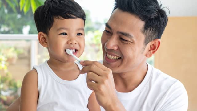 kid and father brushing tooth