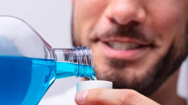 Close-up of a man pouring mouthwash into a cap