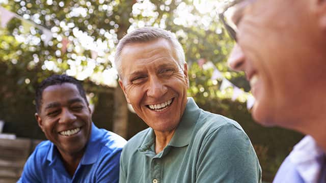 Older male friends socializing in the backyard together