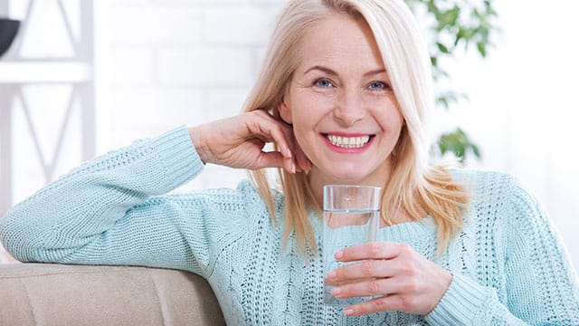 Elder woman smiling while holding a cup of water