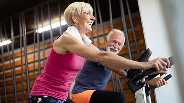 Mature fit couple exercising in gym to stay healthy
