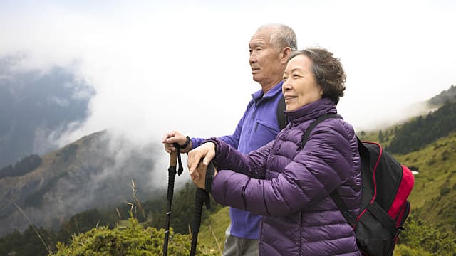 happy asian senior couple hiking on the mountain