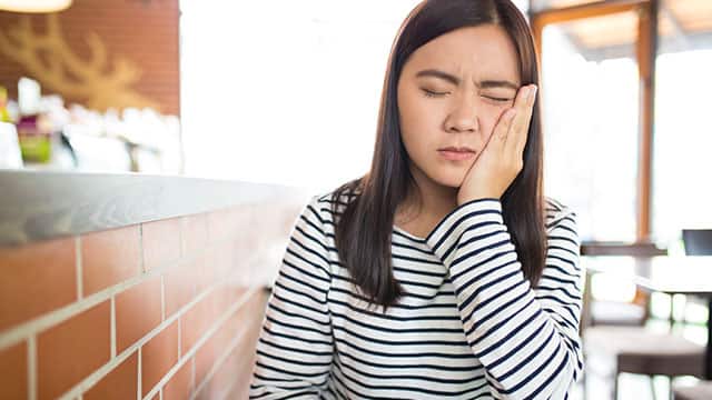 A young woman is having a toothache indoors
