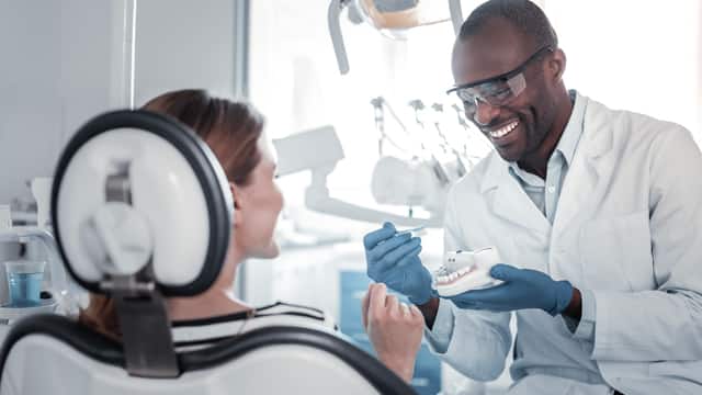 A male dentist talks with a female patient