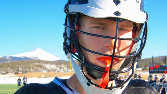 A male teenager in a lacrosse helmet with a mouthguard