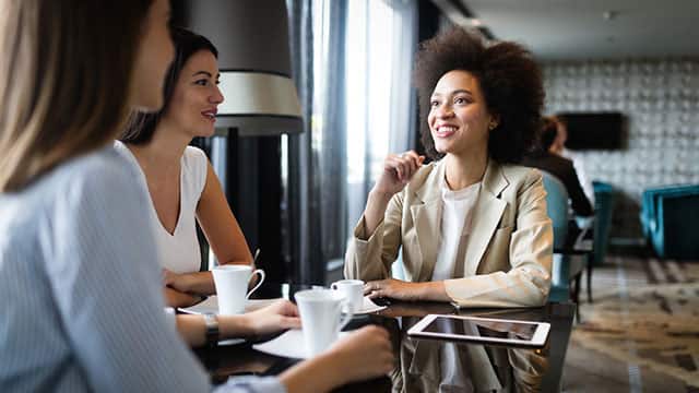 tres mujeres sonriendo durante una reunión