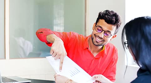 smiling man pointing at something on a piece of paper