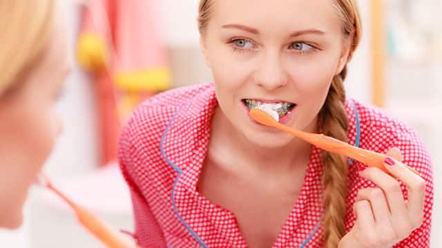 Woman brushing her teeth in front of the bathroom mirror