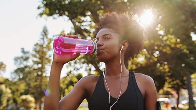Active woman drinking water outside