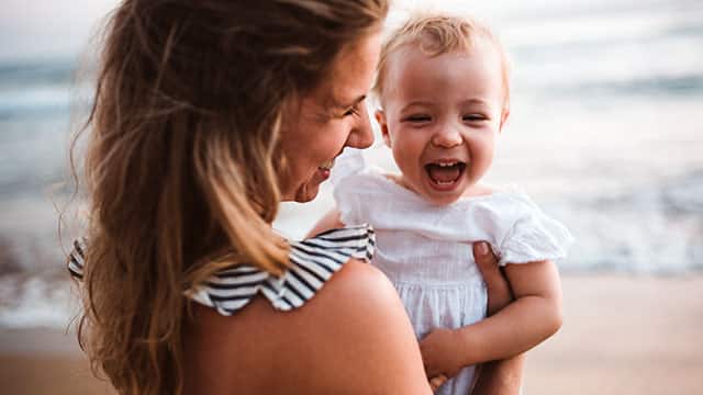 A mom is holding her baby outdoors